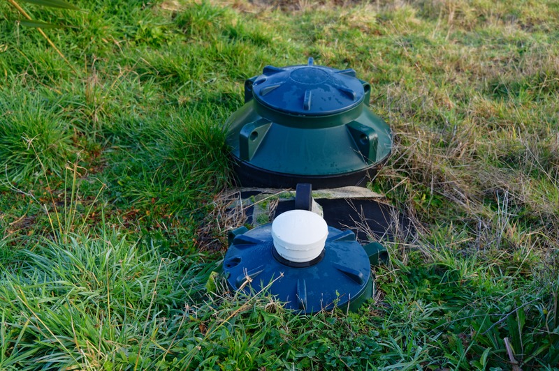 2 large blue septic tanks placed inside a whole in the ground one next to the other