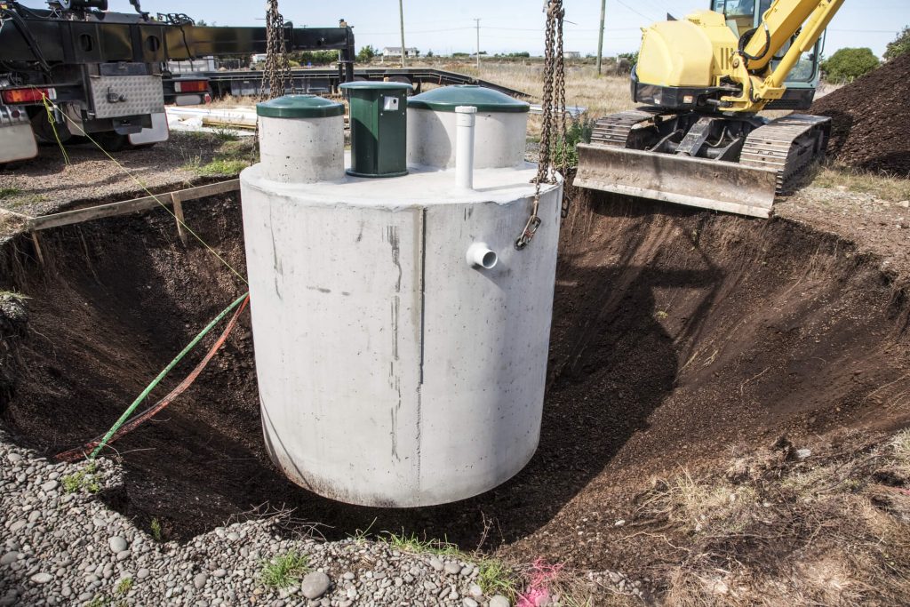 large white septic tank places in a large whole in the mud